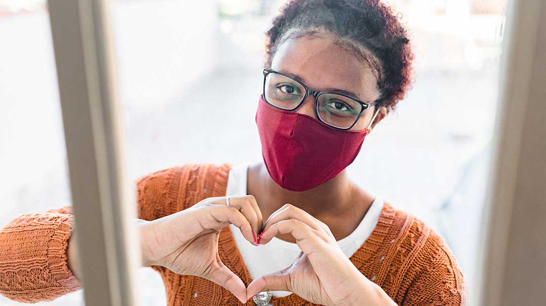 Girl wearing mask making a heart with her hands