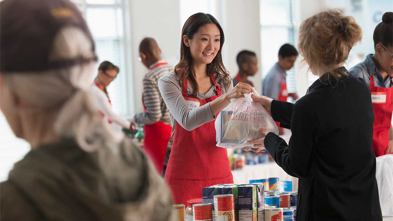 A volunteer hands out food at a food drive