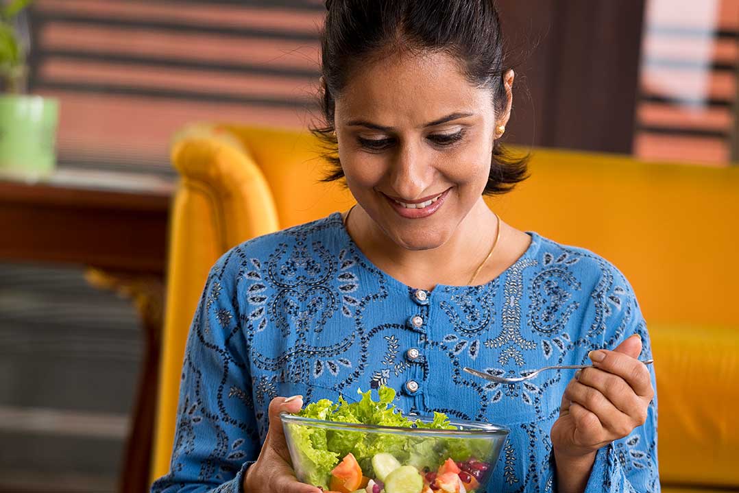Woman smiling while taking a bite out of her salad.
